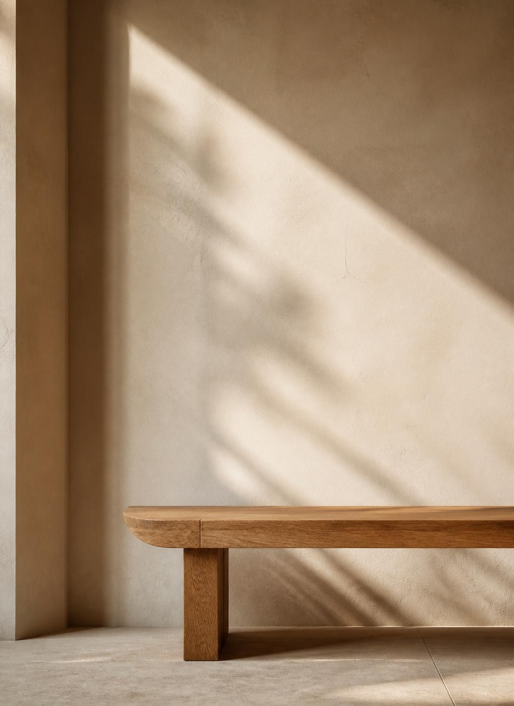 Ivory plaster wall with an oak bench and a long diagonal shadow